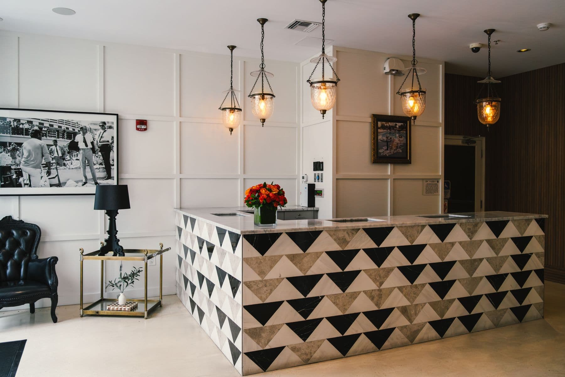A hotel reception desk under pendant lamps, with nobody standing behind it.